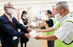 郵便局員にチラシや啓発グッズを手渡す委員ら（右）＝１日、鳥取市用瀬町用瀬の用瀬郵便局