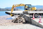 漁港に漂着した流木やごみをショベルカーで撤去する作業員＝２１日、香美町香住区下浜