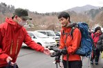 登山者（右）に「無事下山」と書かれたカップ麺を配る警察官＝２９日、大山町大山