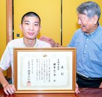 落語甲子園の表彰状を手にする種原さん（左）と、喜ぶ桂文吾さん＝２１日、米子市錦町２丁目の自宅
