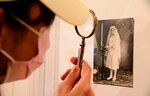 折り目や影も全て絵画のリアルな作品をルーペで見る来場者
