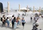 　大阪・関西万博の開幕後初の夏日となり、涼を求めてミストを浴びる来場者＝１９日午後、大阪市此花区の夢洲