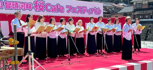 川のせせらぎを背に童謡唱歌を歌うメンバー