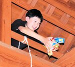 屋根裏からお菓子をまく田渕さん＝２３日、香美町村岡区大笹の地蔵堂