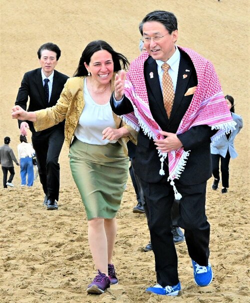 平井知事（右）の案内で砂丘を散策するシファ氏＝２５日、鳥取市の鳥取砂丘