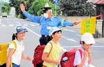 横断歩道で登校中の児童を見守る橋本さん（奥）＝１１日、米子市下新印