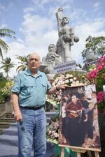 　自身が撮影した写真の横に立つロナルド・ヒーバリーさん＝２０２５年３月、ベトナム・クアンガイ省ティンケ村（共同）