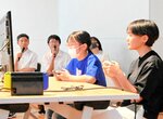 ゲームで対戦する参加者と実況解説する部員（奥）