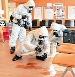 有害な化学物質に見立てた液体を採取する県警のＮＢＣテロ対策部隊の隊員＝１９日、ＪＲ郡家駅