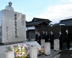 古井氏の胸像を見上げる薛剣大使級総領事（左から３人目）ら＝２８日、八頭町郡家のＪＲ郡家駅