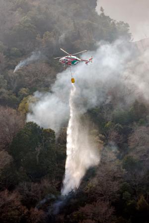　岡山市南区と岡山県玉野市にまたがる山林火災現場で消火活動をするヘリコプター＝２６日午後４時４７分（共同通信社ヘリから）