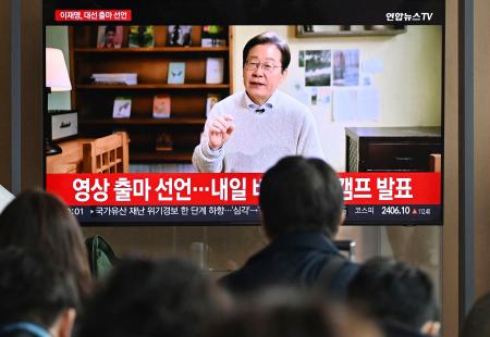 　１０日、ソウル駅の待合室で韓国の「共に民主党」の李在明前代表が大統領選へ出馬表明する映像を見る人たち（共同）