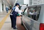 　羽田空港第３ターミナル前で、違法駐車禁止を呼びかけるチラシを配る警察官＝２５日午前