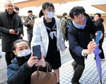 受験番号を見つけて喜ぶ受験生や家族ら＝１７日、鳥取市東町２丁目の鳥取西高