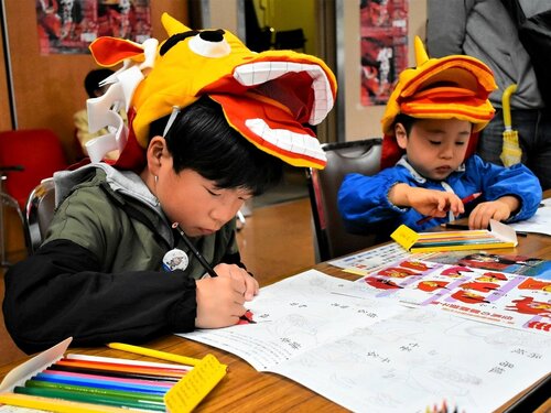 麒麟獅子のかぶり物を身に着けながら塗り絵をする子どもたち