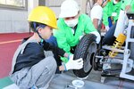 整備士（中央）と一緒にタイヤを取り外す児童＝５日、鳥取市丸山町の中国運輸局鳥取運輸支局