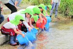 「行ってこーい」とアユを放流する園児たち＝２６日、日野町下菅の黒坂カワコふれあい公園