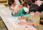 【どこが違う？】時間内に二つの絵を比べ、どこが間違っているか真剣な表情で探す親子連れ