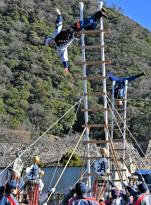 高さ約６メートルのはしごの上で技を披露する消防団員ら＝１４日、鳥取市東町２丁目の擬宝珠橋
