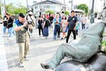 ねずみ男のブロンズ像を写真に撮り、散策を楽しむ米子―香港チャーター便の乗客たち＝１８日、境港市の水木しげるロード