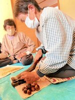 木製の皮むき機を使ってトチの実の皮をむく住民＝１３日、香美町村岡区大笹の大笹地区公民館