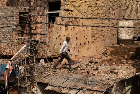 　１０日、カシミール地方のインド側支配地域で、パキスタン軍の攻撃後にがれきの中を歩く男性（ロイター＝共同）