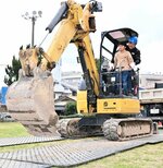 油圧ショベルの操縦席に乗り込み体験乗車する児童
