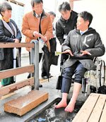 城崎温泉街のバリアフリーの状況を視察する斎藤知事（右）。車いすに乗って関係者と意見を交わした＝今年３月、豊岡市城崎町