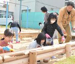メンバーと一緒に砂場の枠に色を塗る児童ら
