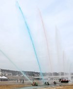 赤や青などに色づけした水を扇形に放水する消防隊員＝６日、倉吉市東巌城町