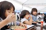 　ギネス記録を目指すイベントで、「おろしそば」をすする子どもたち＝１１日午後、福井駅前