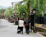 　全国で今年初めての猛暑日となった岐阜県飛騨市内を歩く人たち＝２１日午後
