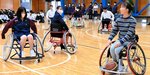 網本選手（右）からアドバイスを受けながら、競技用車イスを操作する生徒ら＝７日、鳥取市東町２丁目の鳥取西高