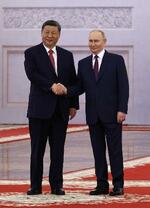 　８日、クレムリンでの首脳会談前の歓迎式典で、握手する中国の習近平国家主席（左）とロシアのプーチン大統領＝モスクワ（ロイター＝共同）