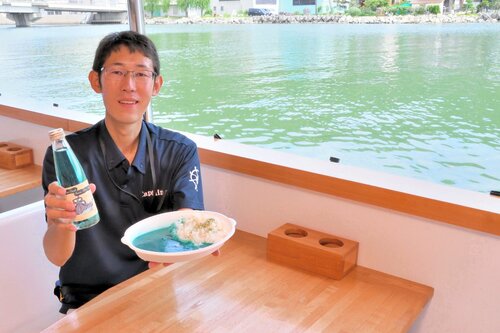 船内で提供される岩美ブルーサイダーと岩美ブルーカレーを持つ田中船長＝１２日、岩美町大谷