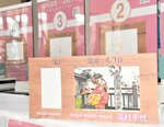 色の異なる七つのスタンプ（奥）を重ねて押すと出来上がるスタンプカードの完成品（手前右）と台紙