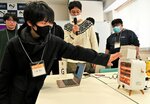 ストーブに近づきすぎないようチェックする作品を説明する製作チーム