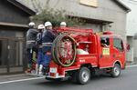 　岡山市南区の山林火災で、消防車に乗り込み現場へ向かう消防団員＝３月２８日