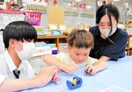 高校生の指導でトイレットペーパーの芯を使ったけん玉を作る子ども＝４日、鳥取市伏野のリファーレンいなば
