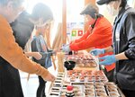 はまさか艶美とガラエビを受け取る来場者＝１６日、新温泉町栃谷の道の駅山陰海岸ジオパーク浜坂の郷
