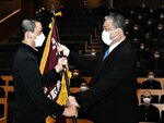 石浦校長から選抜旗を受け取る河西主将（左）＝鳥取城北高のホールグランデ