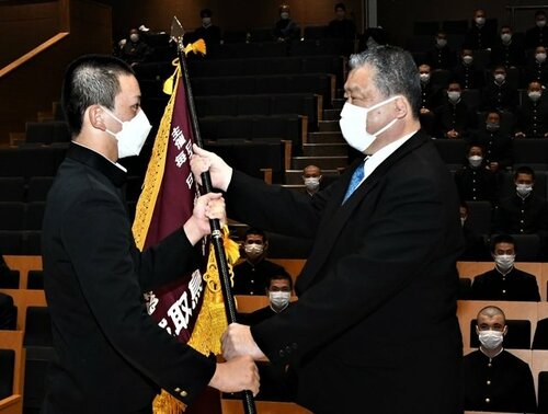 石浦校長から選抜旗を受け取る河西主将（左）＝鳥取城北高のホールグランデ