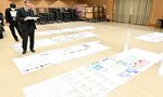会場に並べられた研究を審査する審査員ら