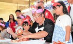 頭にかぶり物をのせ、カニの食べ方を競う参加者ら＝１６日、香美町香住区若松の香住漁港西港