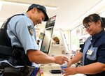制服を着用して飲料水を購入し、従業員（右）と会話する警察官