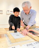 インク付け作業を行い版画の魅力を体験する来場者
