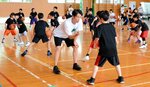 薮内ヘッドコーチ（中央）に体のばねの使い方を教わる児童