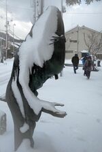 雪に埋もれる水木しげるロードの妖怪ブロンズ像＝24日午前10時32分、境港市大正町