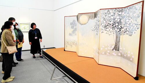 学芸員の解説に耳を傾けながら作品に見入る来場者＝４日、倉吉博物館