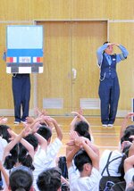 車の後退灯について解説する警察官＝１８日、大阪市西区の本田小